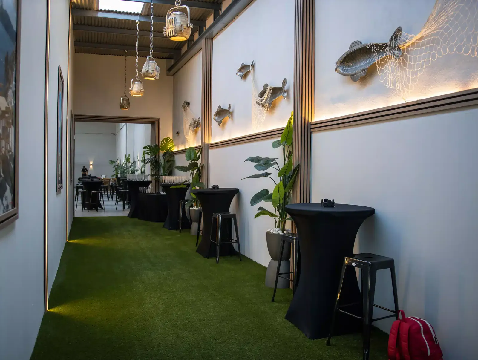 Pasillo de LA NAVE 77 con peces de metal, redes de pesca y lámparas industriales: decoración con concepto propio